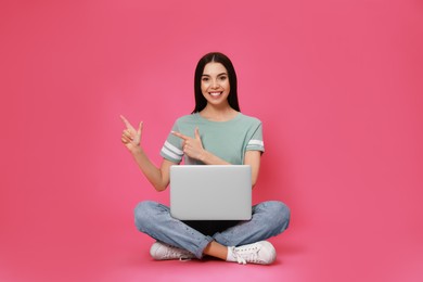 Photo of Young woman with modern laptop on pink background