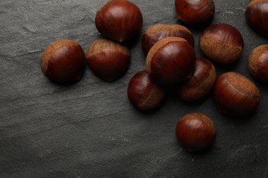 Roasted edible sweet chestnuts on grey textured table, flat lay. Space for text