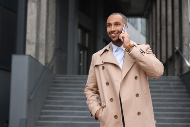 Photo of Happy man talking on smartphone outdoors, space for text. Lawyer, businessman, accountant or manager