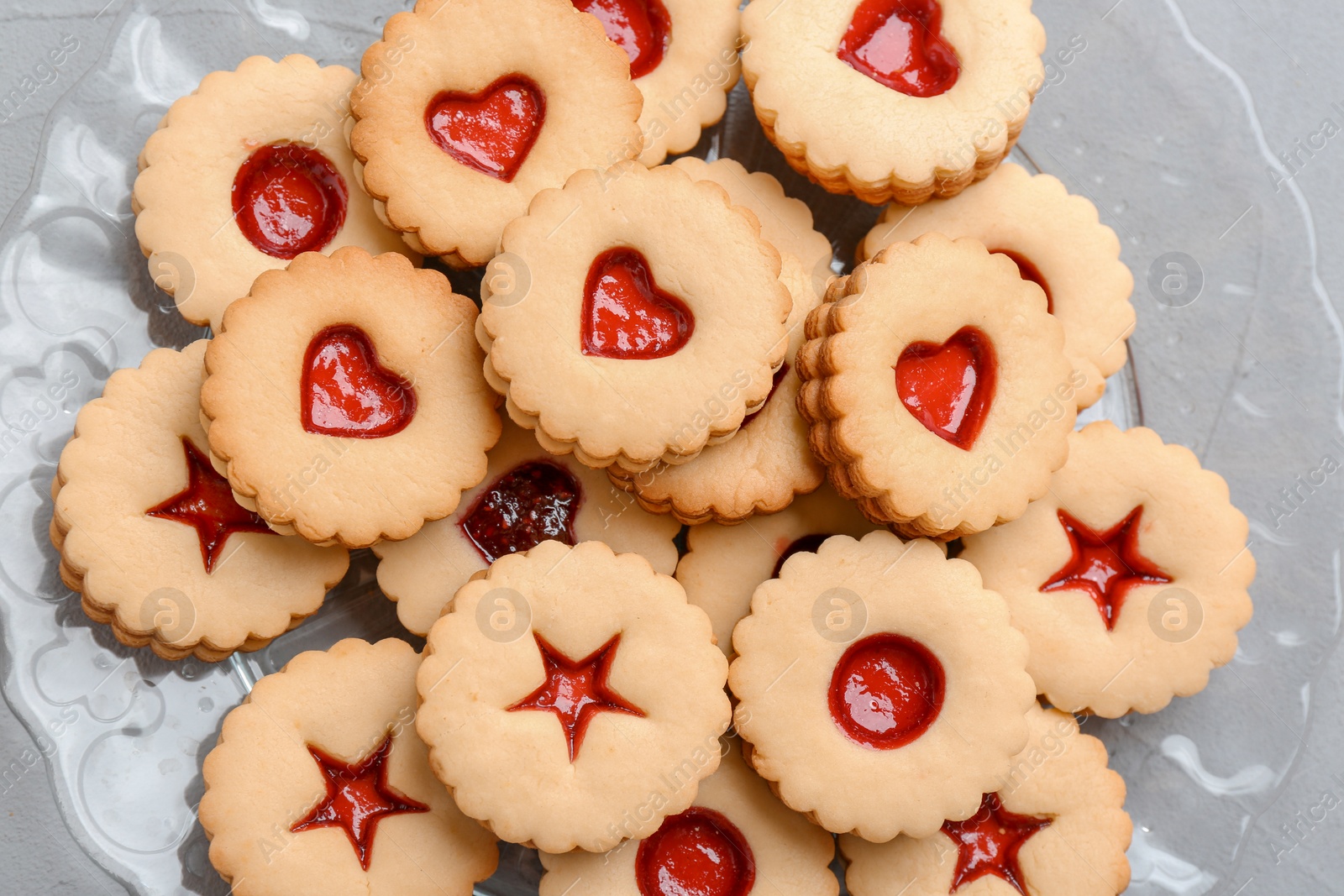 Photo of Traditional Christmas Linzer cookies with sweet jam on plate, top view