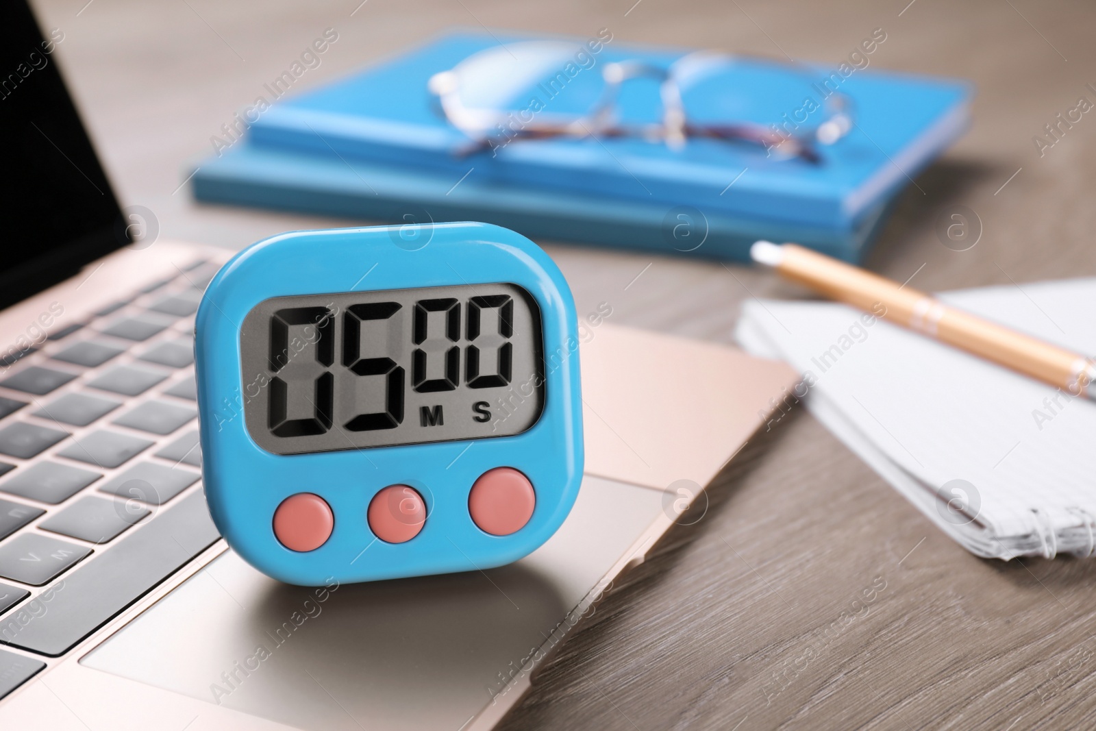 Photo of Kitchen timer and laptop on wooden table, closeup. Space for text