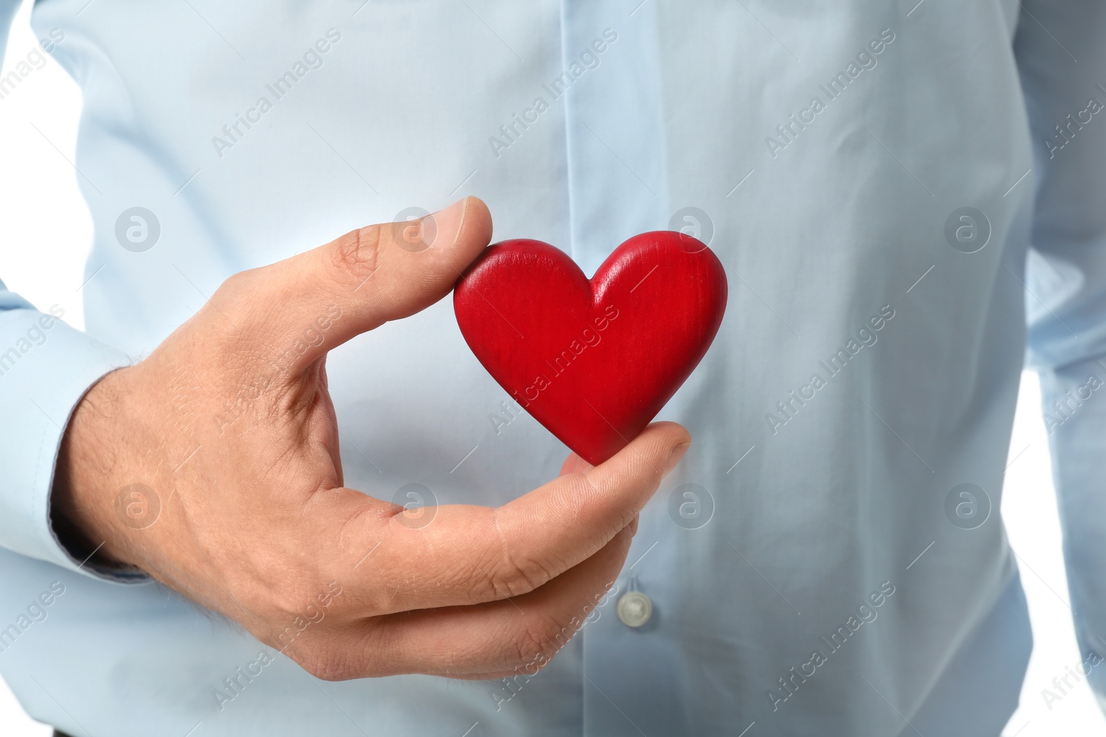 Photo of Young man holding red heart, closeup. Donation concept