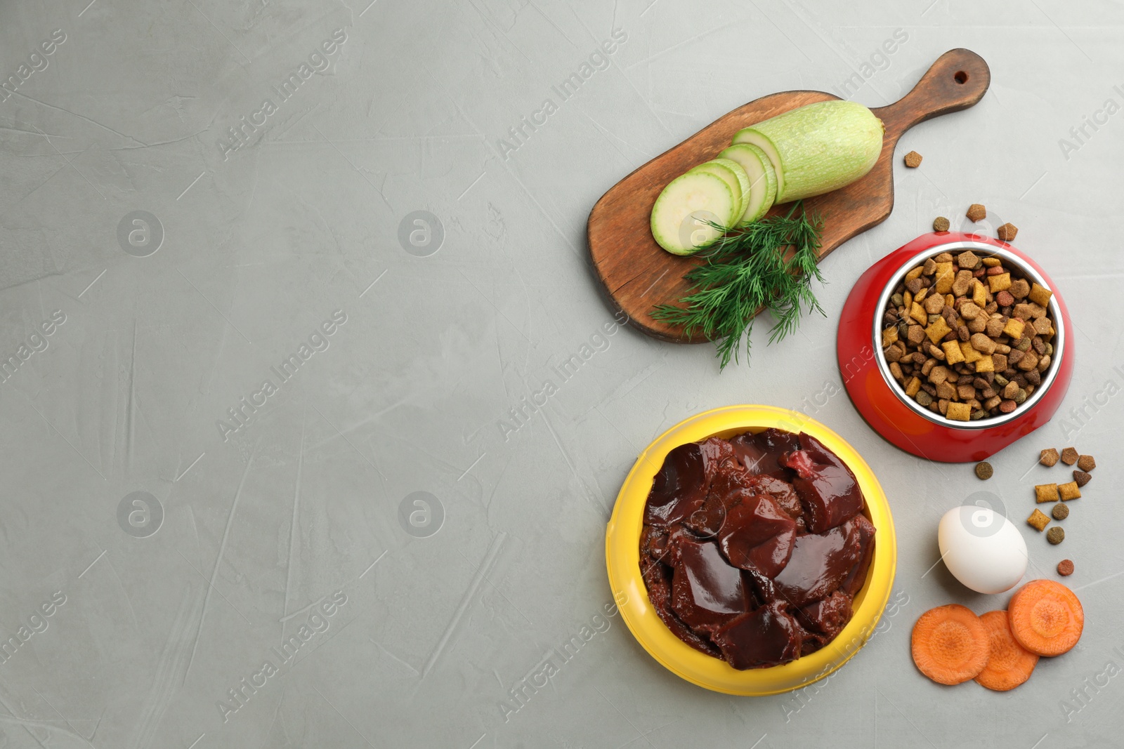 Photo of Pet food and natural ingredients on grey table, flat lay. Space for text