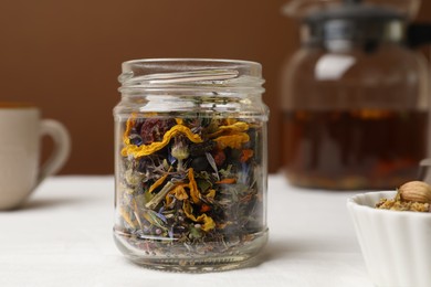 Photo of Jar with dried herbs on white table