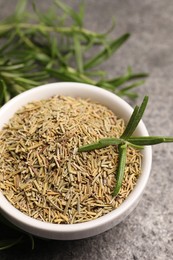 Photo of Dry and fresh rosemary in bowl on gray table, closeup