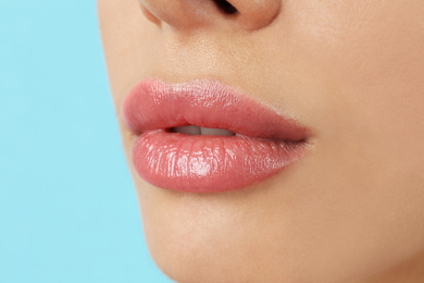 Photo of Woman with beautiful full lips on light blue background, closeup