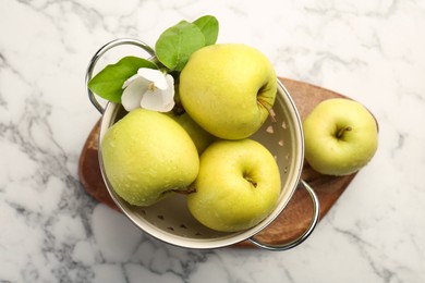 Photo of Colander with fresh apples and beautiful spring blossom on white marble table, top view