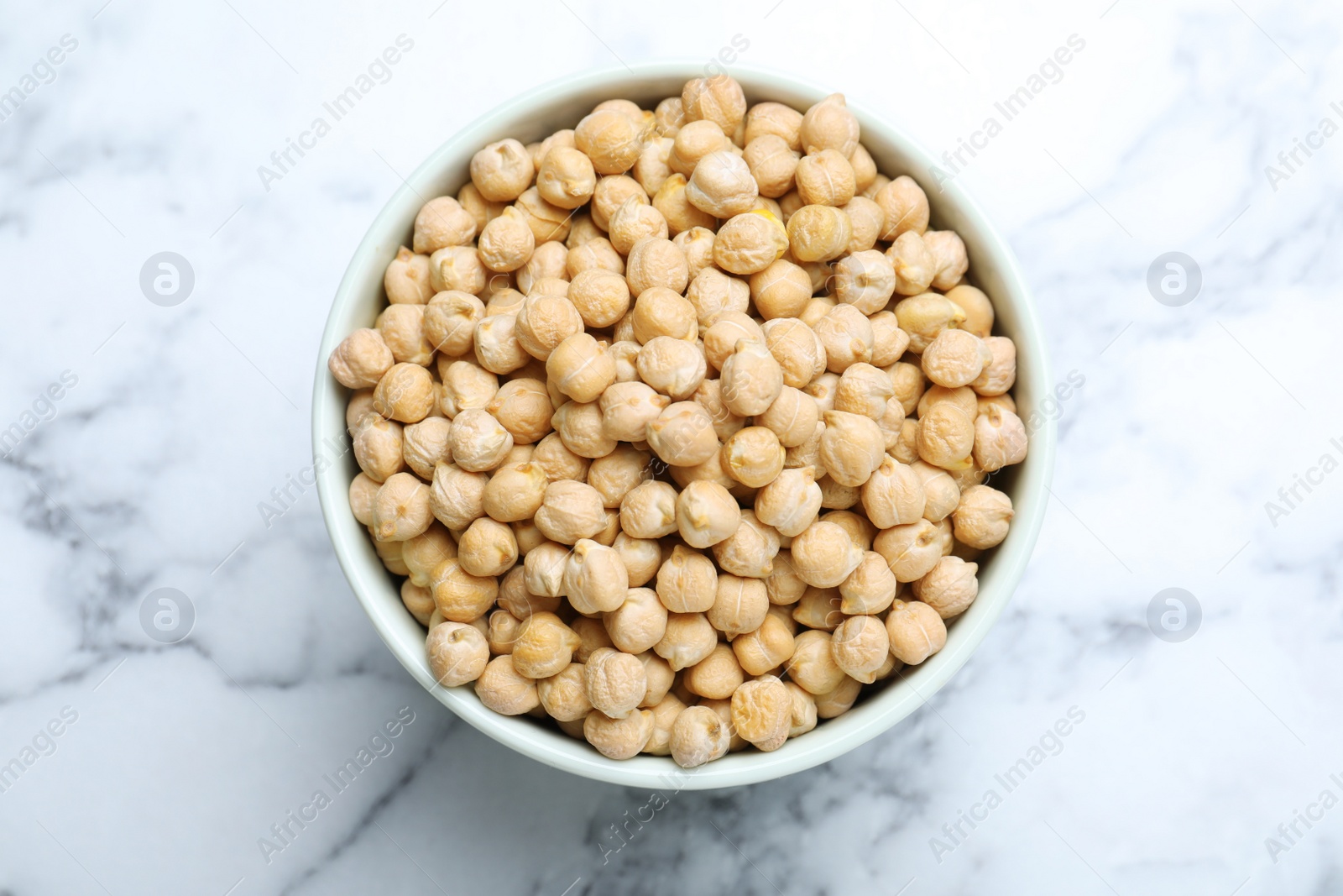 Photo of Chickpeas in bowl on white marble table, top view