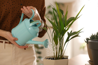Photo of Young woman watering plant at home, closeup. Engaging hobby