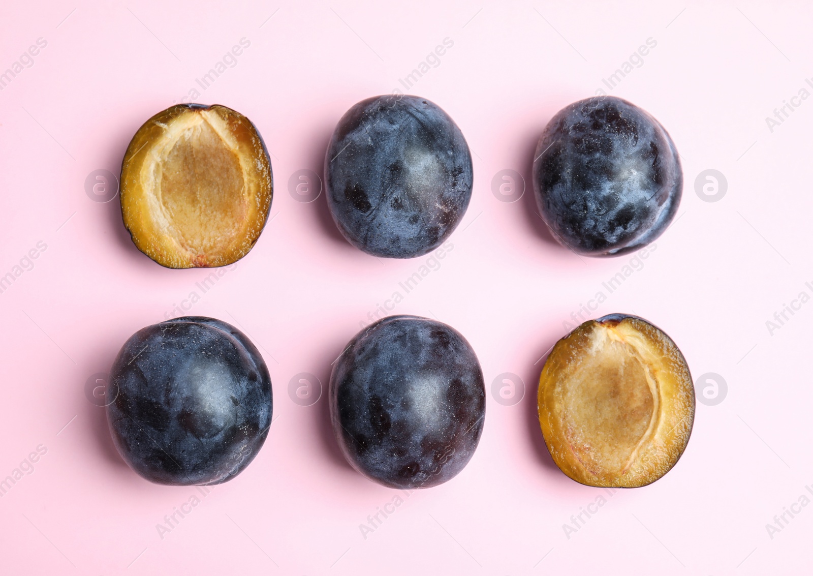 Photo of Delicious ripe plums on pink background, flat lay