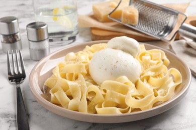 Photo of Delicious pasta with burrata cheese on white marble table
