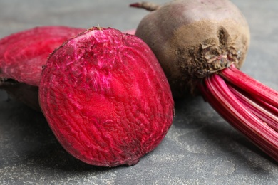 Photo of Cut and whole raw beets on grey table, closeup