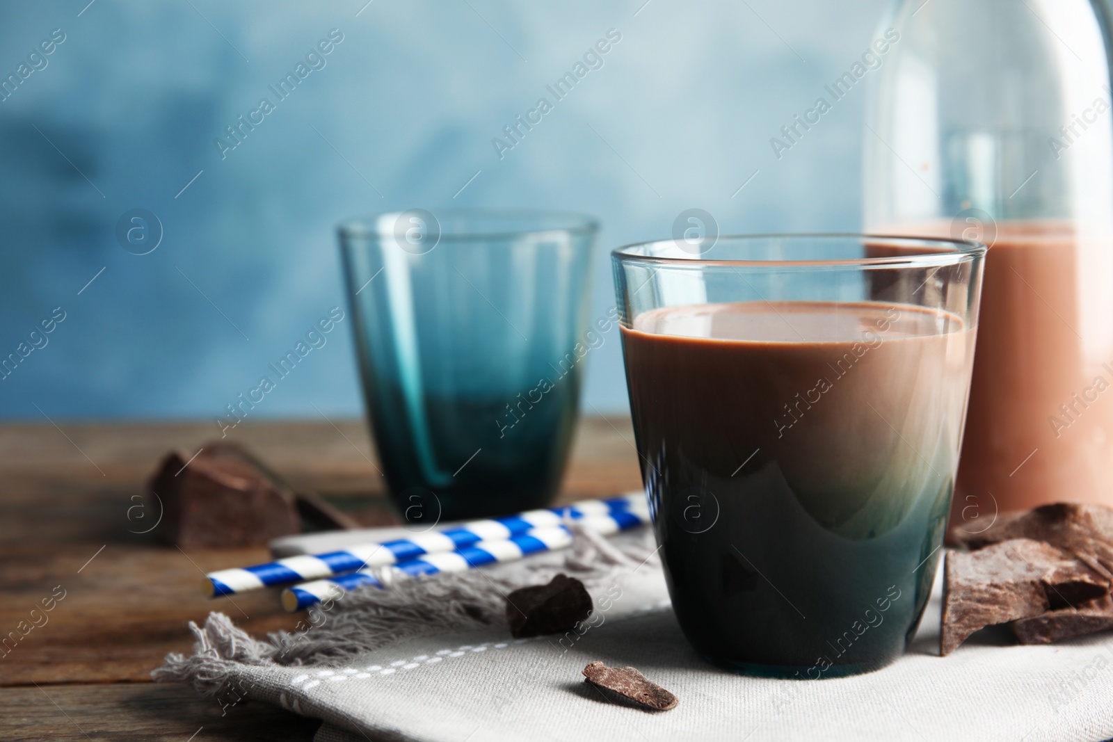 Photo of Glass of tasty chocolate milk on wooden table, space for text. Dairy drink