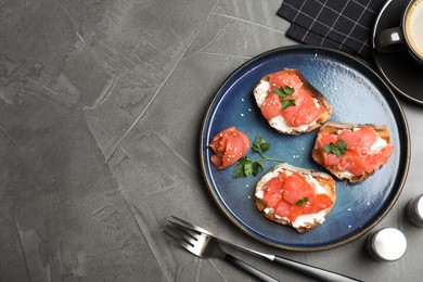 Photo of Tasty bruschettas with salmon, cream cheese and parsley on grey table, flat lay. Space for text