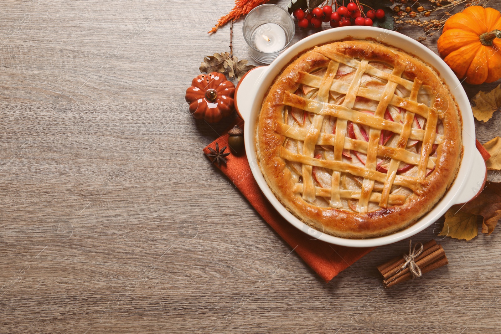 Photo of Delicious homemade apple pie and autumn decor on wooden table, flat lay. Space for text