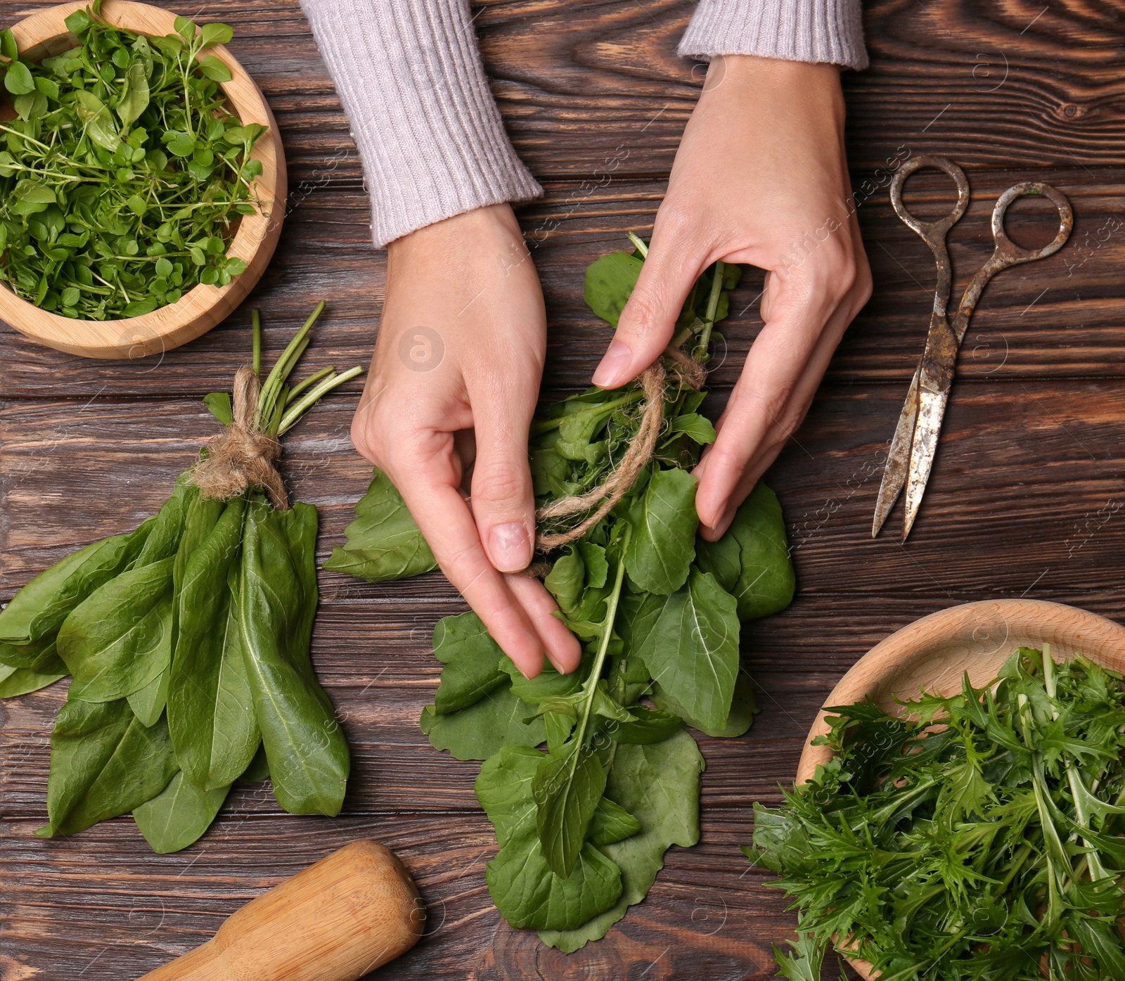 Photo of Woman with fresh green herbs at wooden table, top view