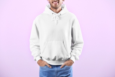 Man in hoodie sweater on color background. Space for design