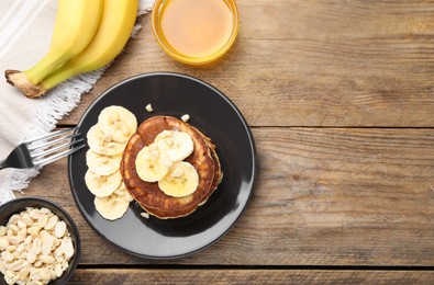 Photo of Plate of banana pancakes and honey served on wooden table, flat lay. Space for text