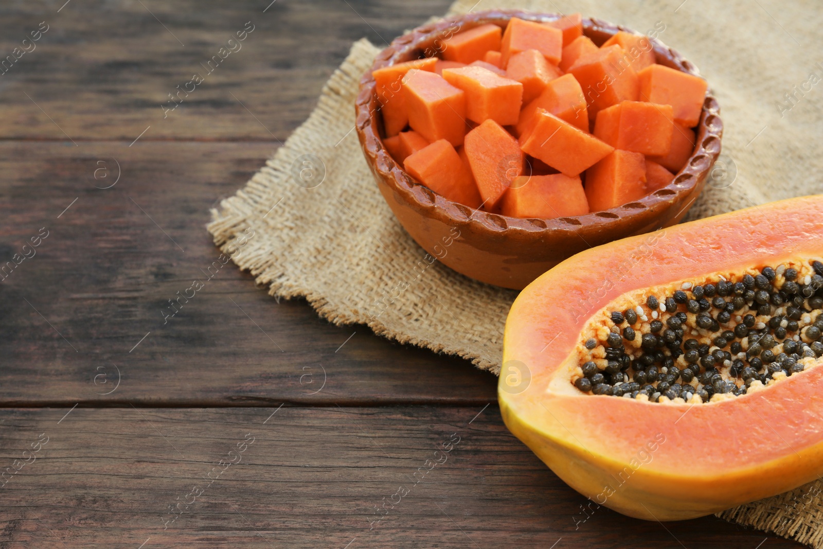 Photo of Tasty ripe cut papaya fruits on wooden table. Space for text