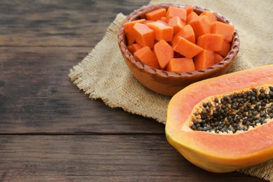 Photo of Tasty ripe cut papaya fruits on wooden table. Space for text