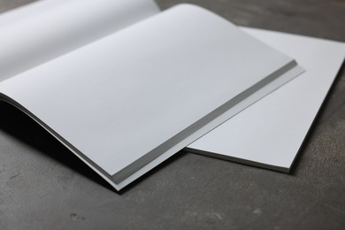 Photo of Open notebook with blank paper sheets on grey textured table, closeup. Mockup for design