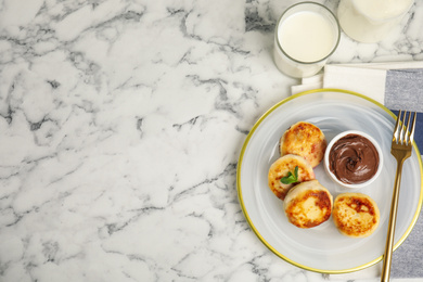 Delicious cottage cheese pancakes with chocolate paste on white marble table, flat lay. Space for text