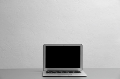Photo of Modern laptop with blank screen on table against gray background