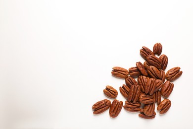 Photo of Pile of delicious fresh pecan nuts on white background, flat lay. Space for text