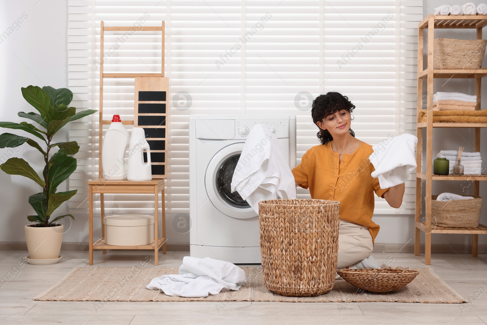 Photo of Woman with laundry near washing machine indoors