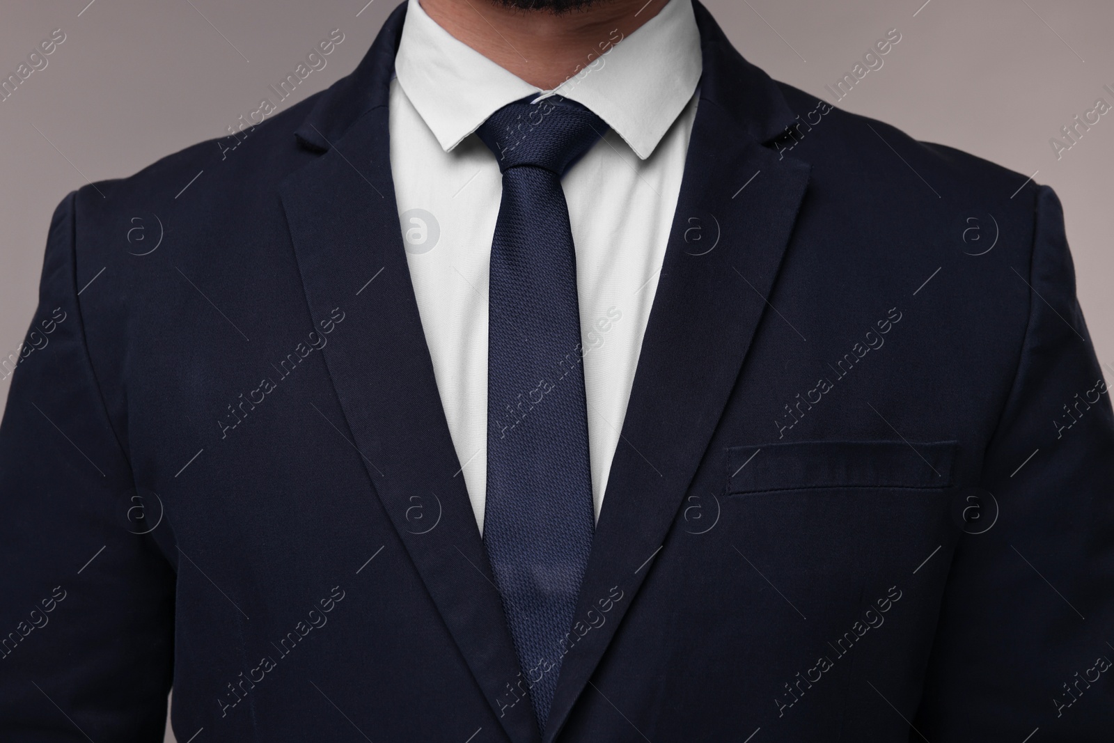 Photo of Businessman in suit and necktie on grey background, closeup