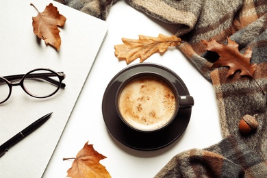 Photo of Flat lay composition with notebook, cup of coffee and warm blanket on white background