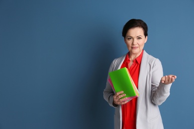 Photo of Portrait of female teacher with notebooks on color background