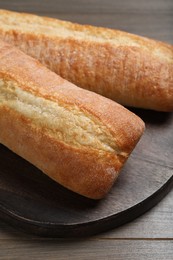 Photo of Tasty baguettes on wooden table, closeup. Fresh bread