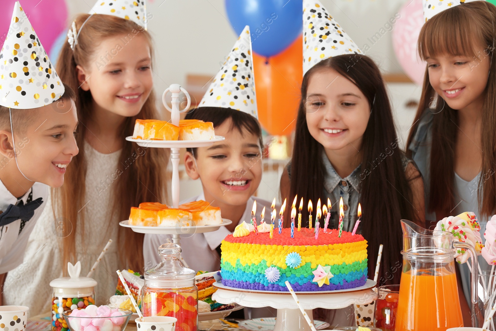 Photo of Happy children near cake with candles at birthday party indoors