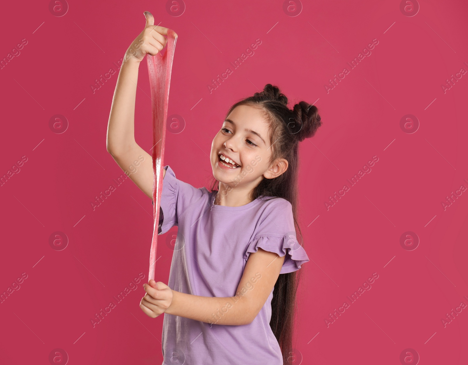 Photo of Little girl with slime on pink background