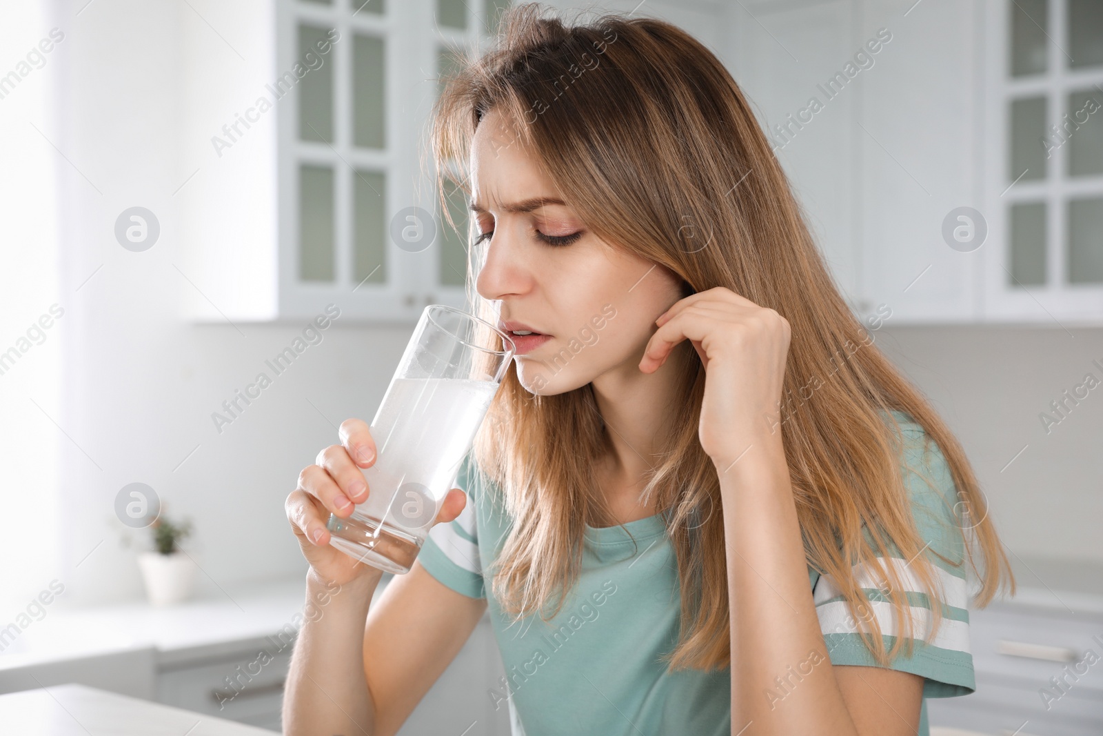 Photo of Woman taking medicine for hangover in kitchen