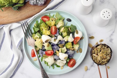 Photo of Delicious salad with cauliflower, tomato and cheese served on white marble table, flat lay