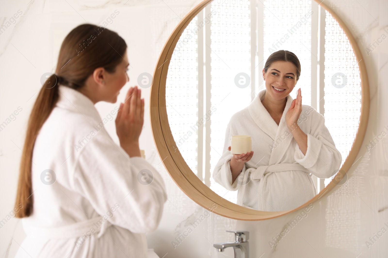 Photo of Young pregnant woman with cosmetic product in bathroom