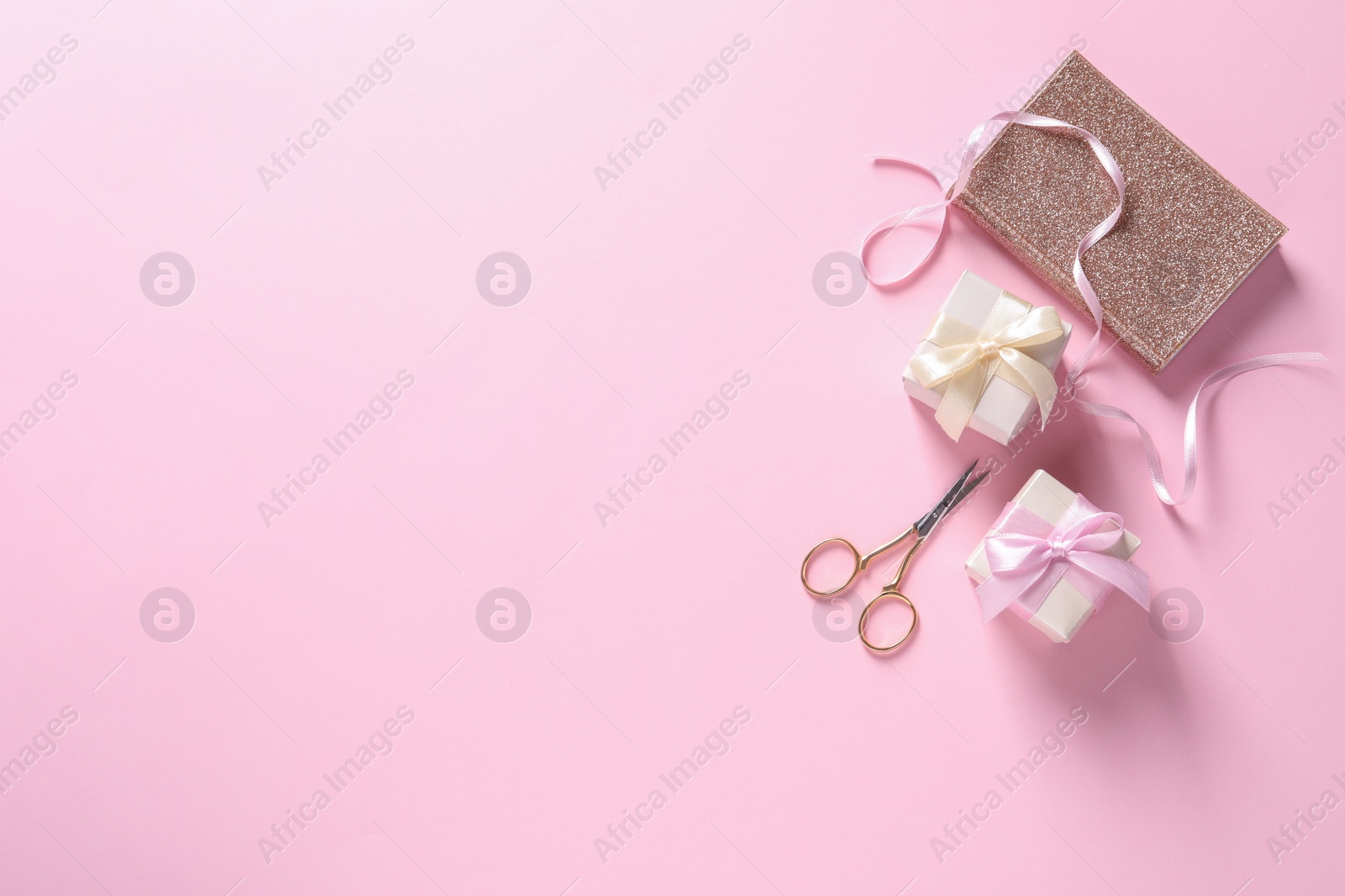 Photo of Flat lay composition with scissors, gifts and notebook on pink background, space for text