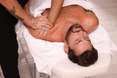 Photo of Man receiving professional massage on couch in spa salon