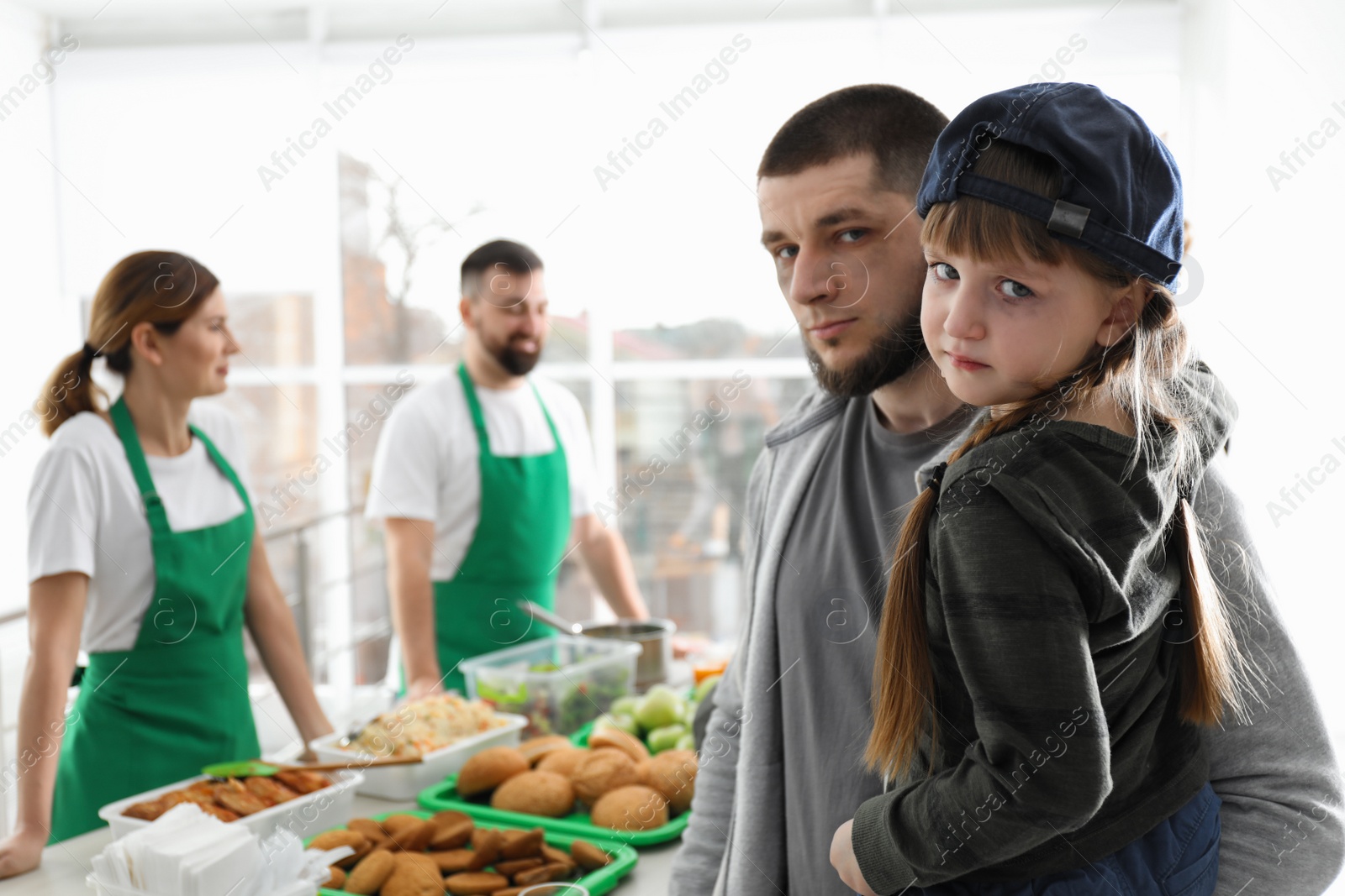 Photo of Poor father and daughter receiving food from volunteers indoors