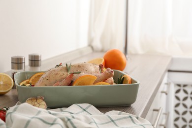 Photo of Chicken with orange slices in baking pan on wooden countertop