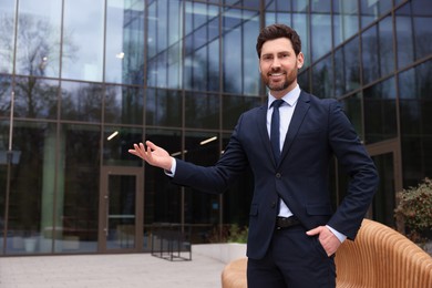 Photo of Happy real estate agent in suit outdoors