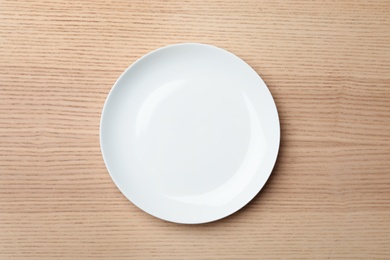 Stylish ceramic plate on wooden background, top view