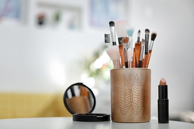 Holder with makeup brushes on table