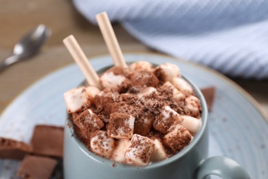 Photo of Cup of aromatic hot chocolate with marshmallows and cocoa powder served on table, closeup