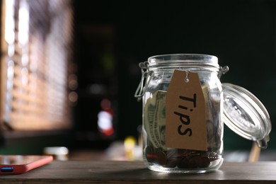 Glass jar with tips on wooden table indoors, closeup. Space for text