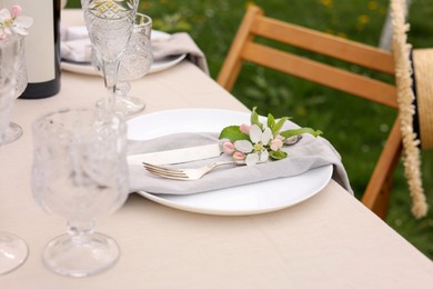 Photo of Stylish table setting with beautiful spring flowers, wine, plates and glasses in garden