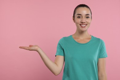 Special promotion. Smiling woman holding something on pink background. Space for text