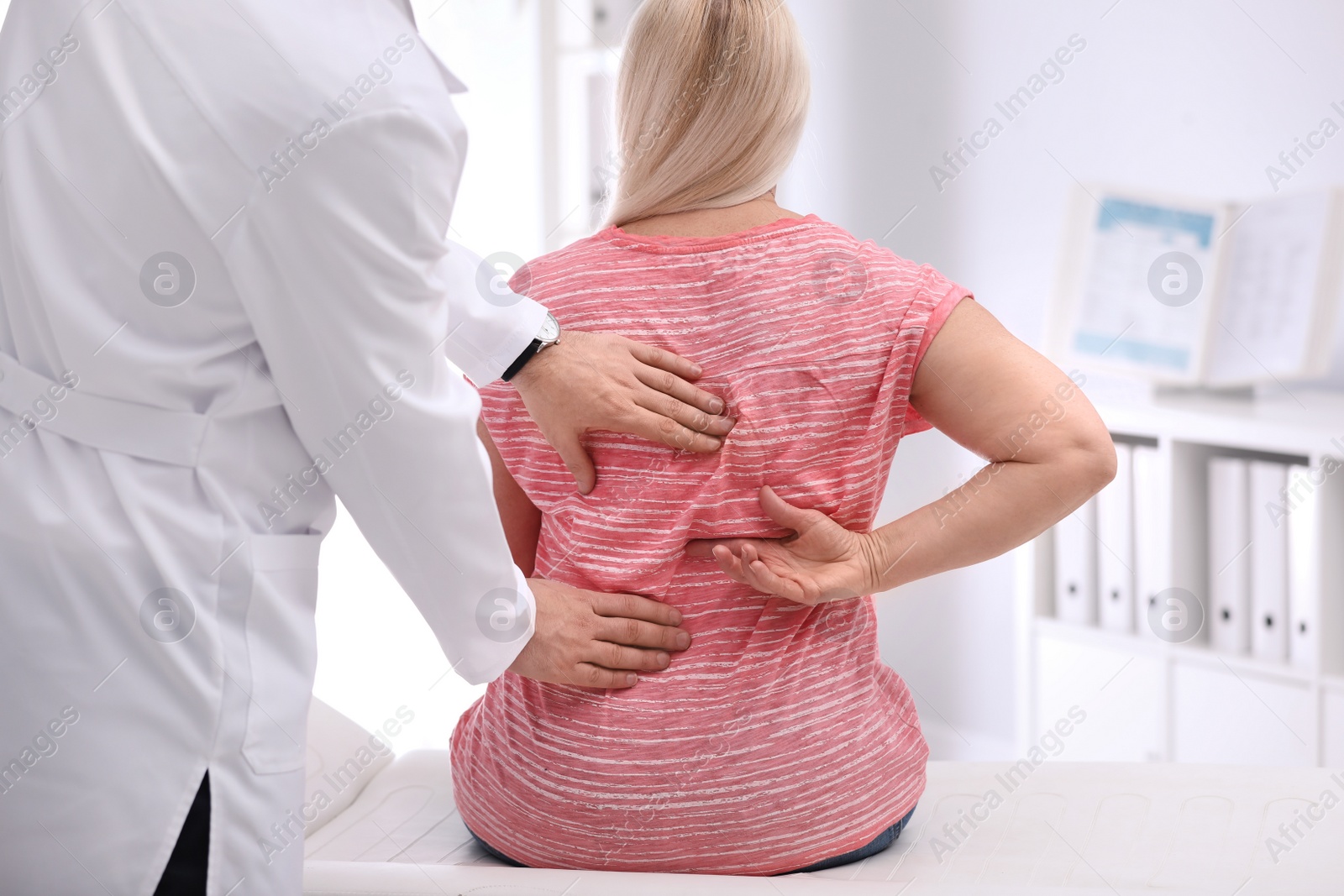 Photo of Chiropractor examining patient with back pain in clinic